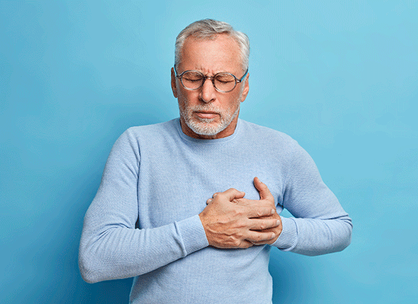 A imagem tem o fundo azul no qual há um senhor de blusa azul e com a mão no coração.